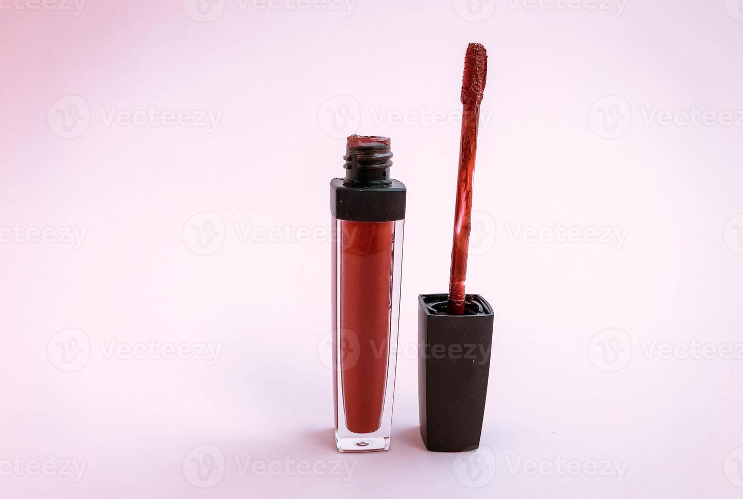 Brush for make-up lips above the bottle of liquid lipstick close-up on a pink background with copyspace photo