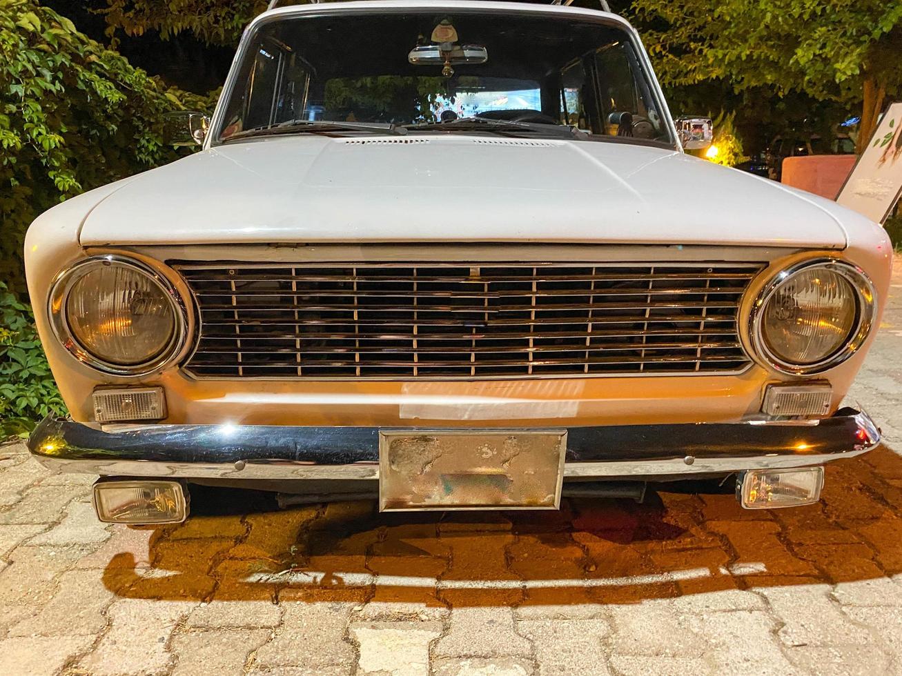 Old white retro restored classic car from 60s, 70s, 80s, 90s with round headlights and chrome grille photo