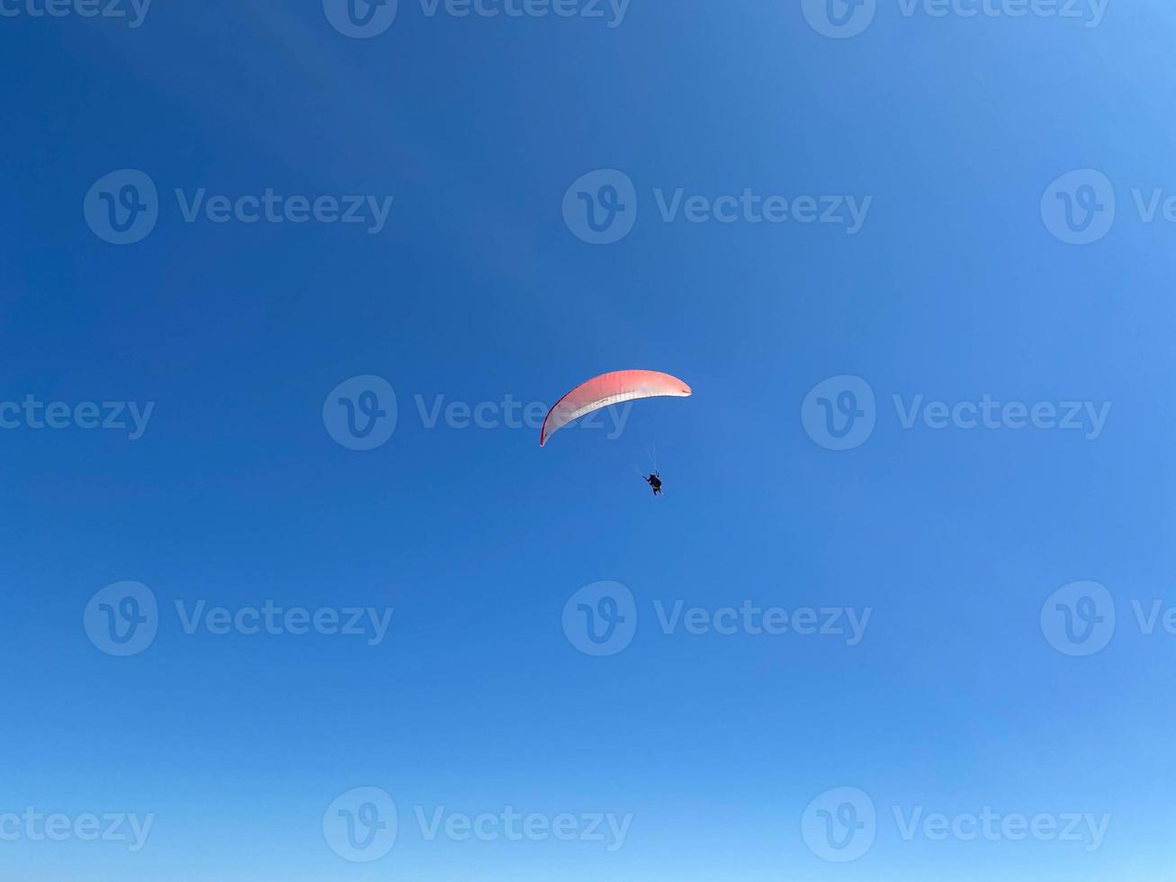 Parachutist is flying slowly down with an open parachute. Skydiving, gliding, parachute jump photo