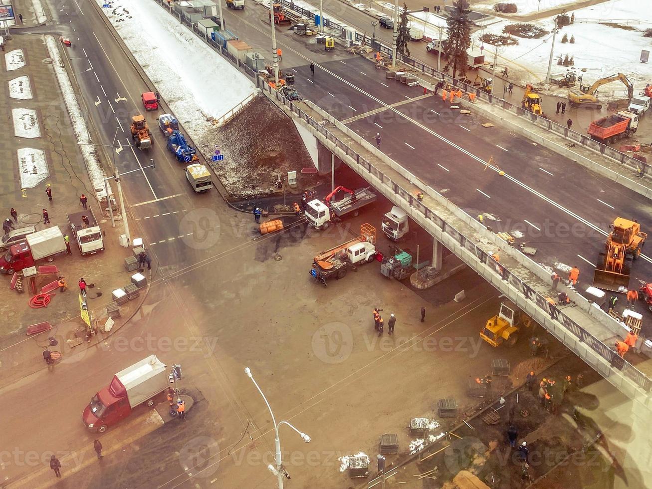 construction of a new bridge in the city center, view from above. construction machinery is working on laying new asphalt. congestion of cars under the bridge photo