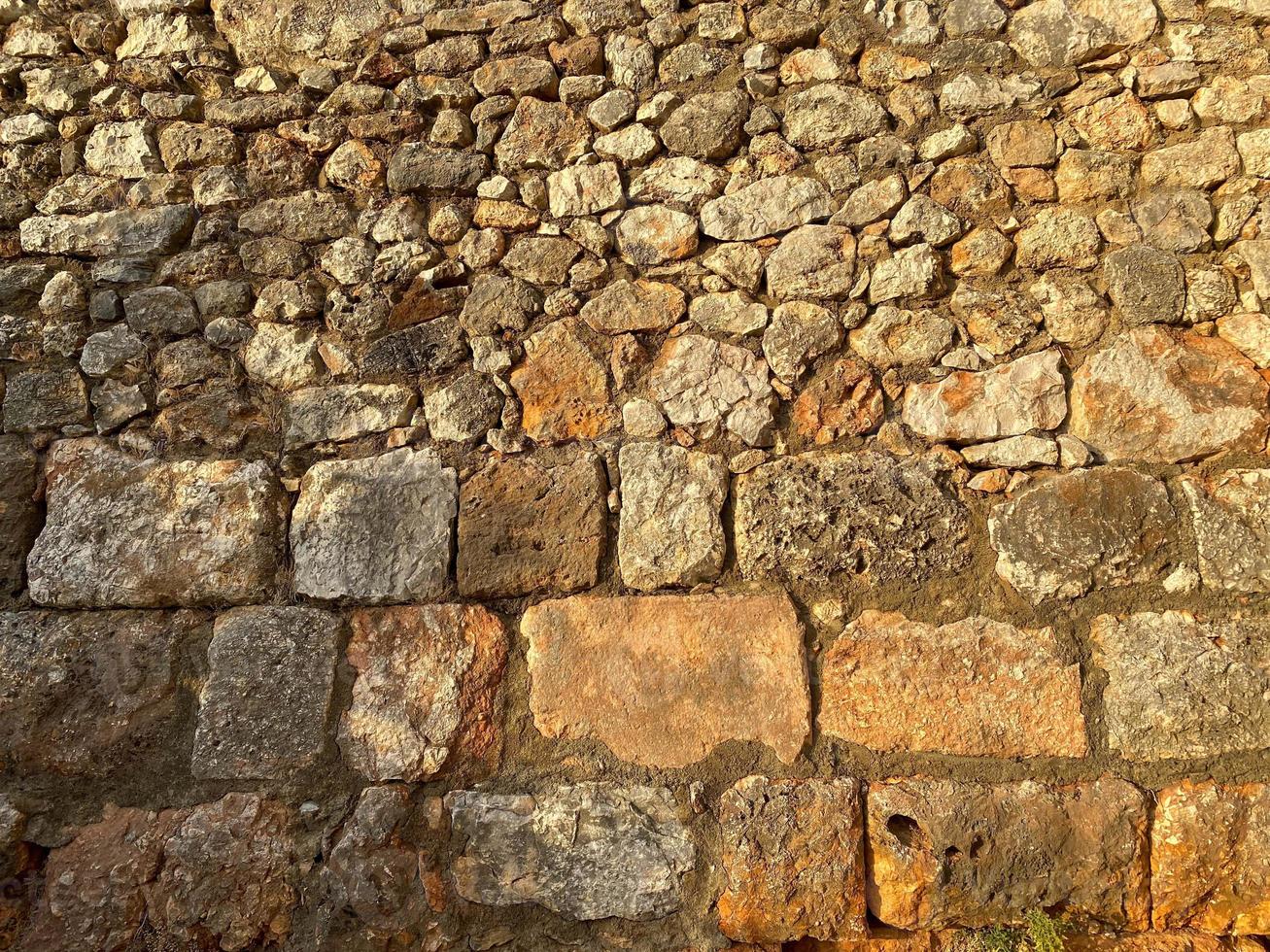 Background, texture, stone wall of round stones cobblestones bricks natural surface natural sharp convex rough stone cobblestone with cracks photo