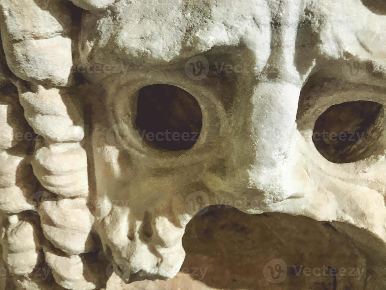 textura tridimensional, escultura de yeso, arte antiguo. en la textura de rasguños, astillas, grietas. una espeluznante máscara de yeso con la boca abierta y grandes cuencas oculares. cara de terror foto