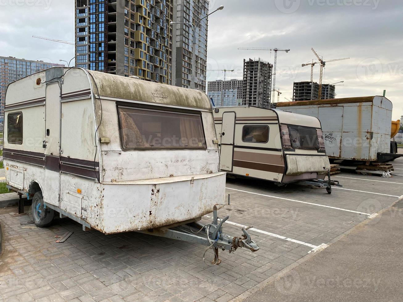 Old white rusty caravan trailers, mobile homes are parked photo