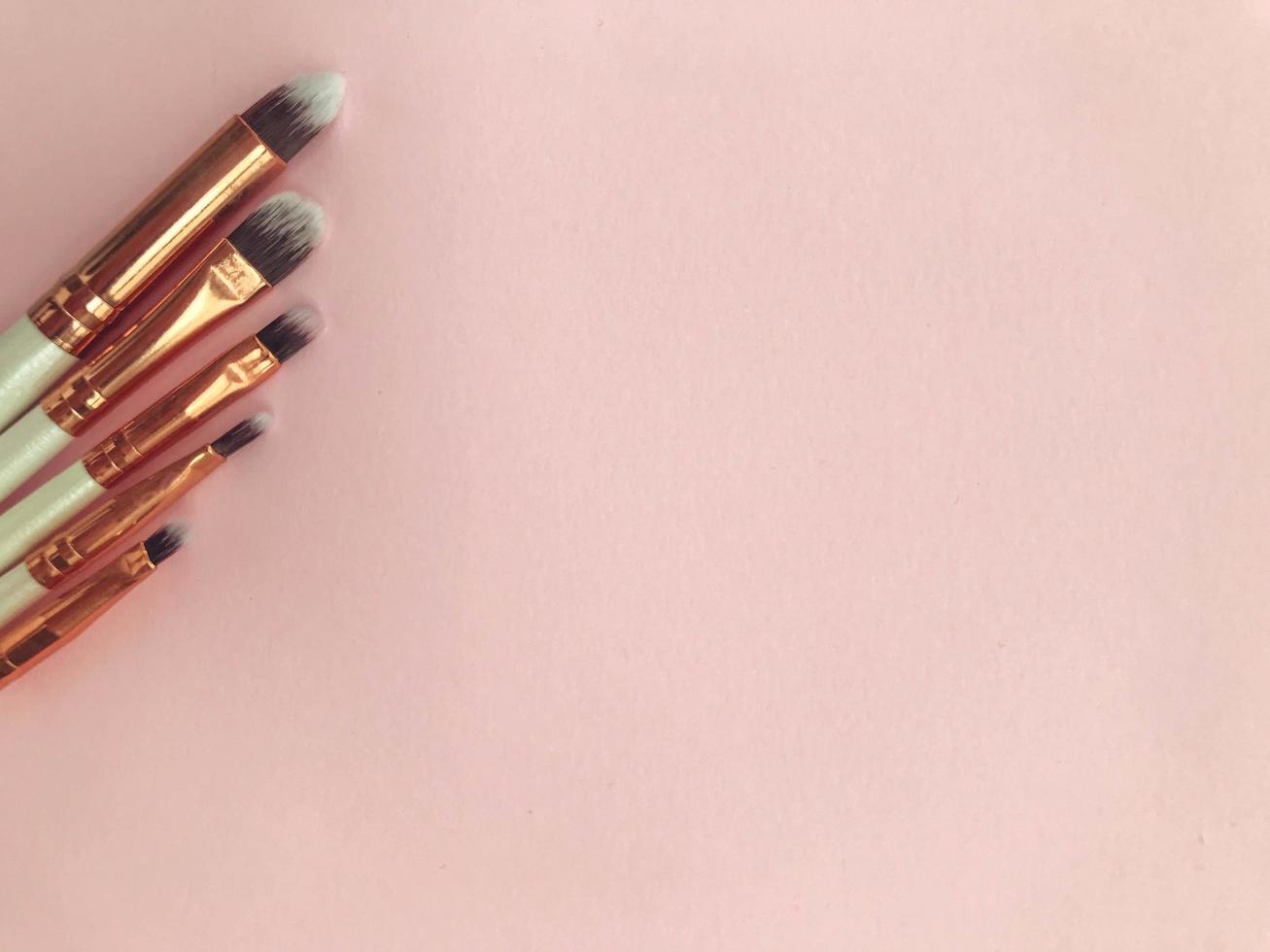 makeup brushes on a pink background. different brushes for applying textures to the face. keg eyeshadow brush, flat lipstick brush, fine eyeliner brush photo