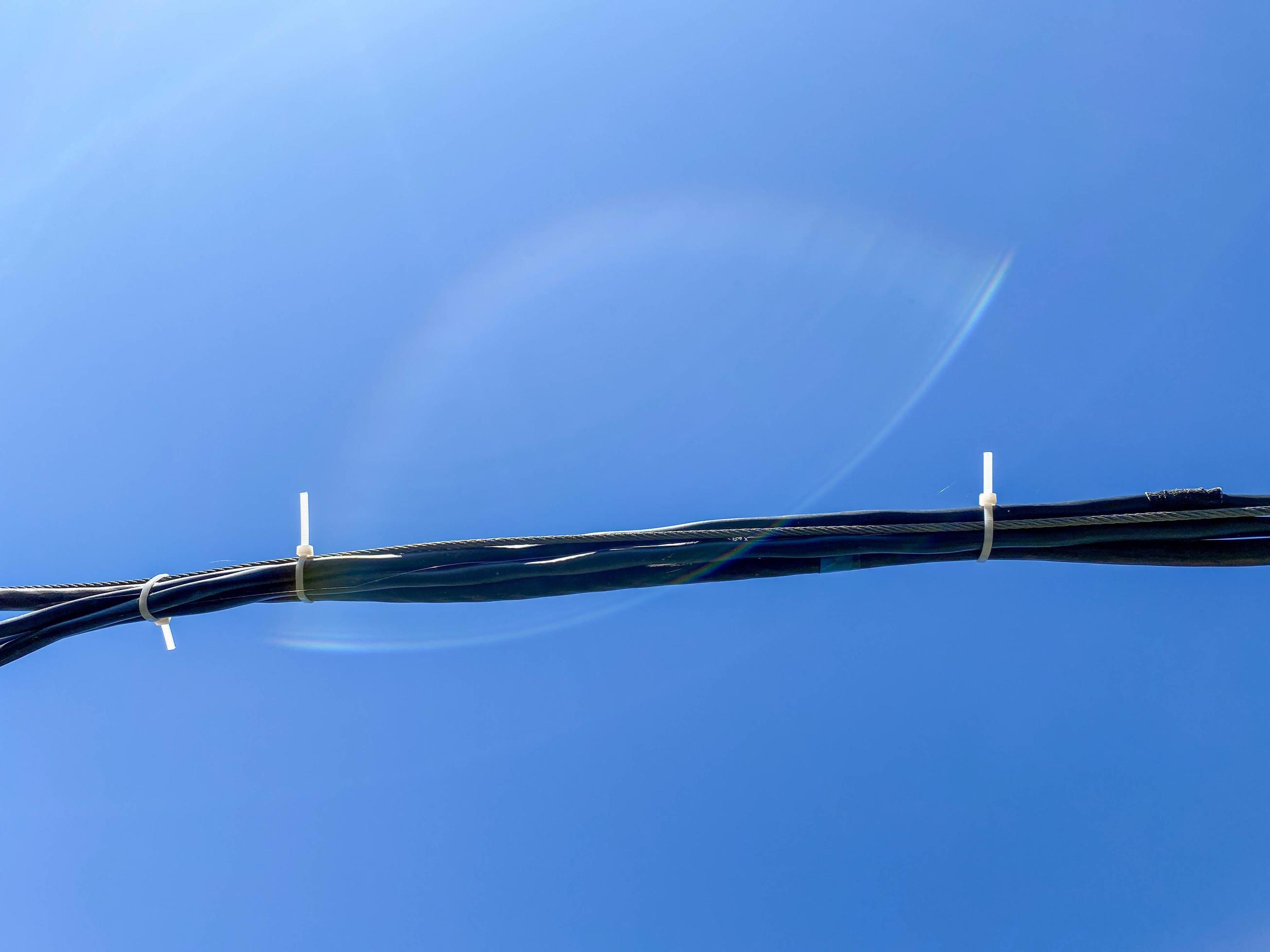 Thick black electrical industrial high voltage wire cable on a blue sky