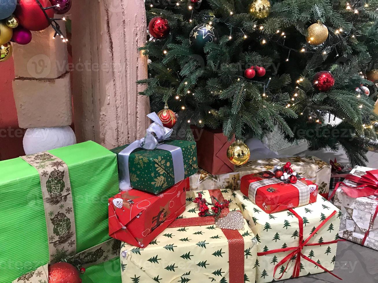 Christmas colored wrapped presents and gifts under the Christmas tree. Christmas background - baubles and multicolor balls on the Christmas tree with shining lights photo