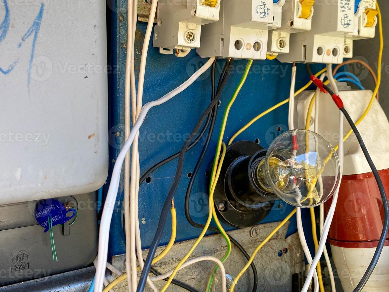 A light bulb in a homemade electric control cabinet for electronic devices with circuit breakers and counters in an iron box photo
