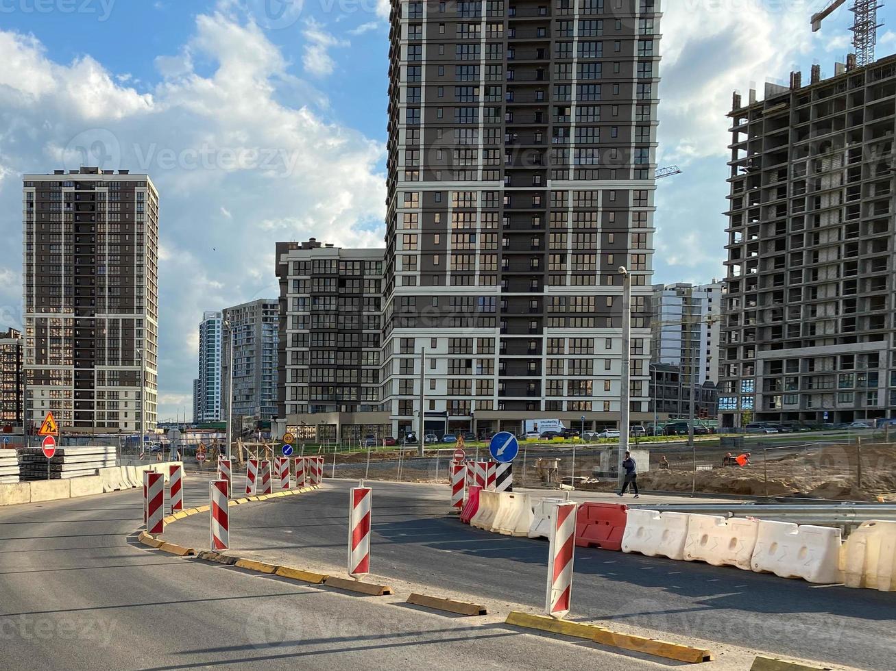 Repair and construction of a road with temporary road signs and cones against the background of beautiful tall new buildings against the background of blue sky and rainbow in a big city photo
