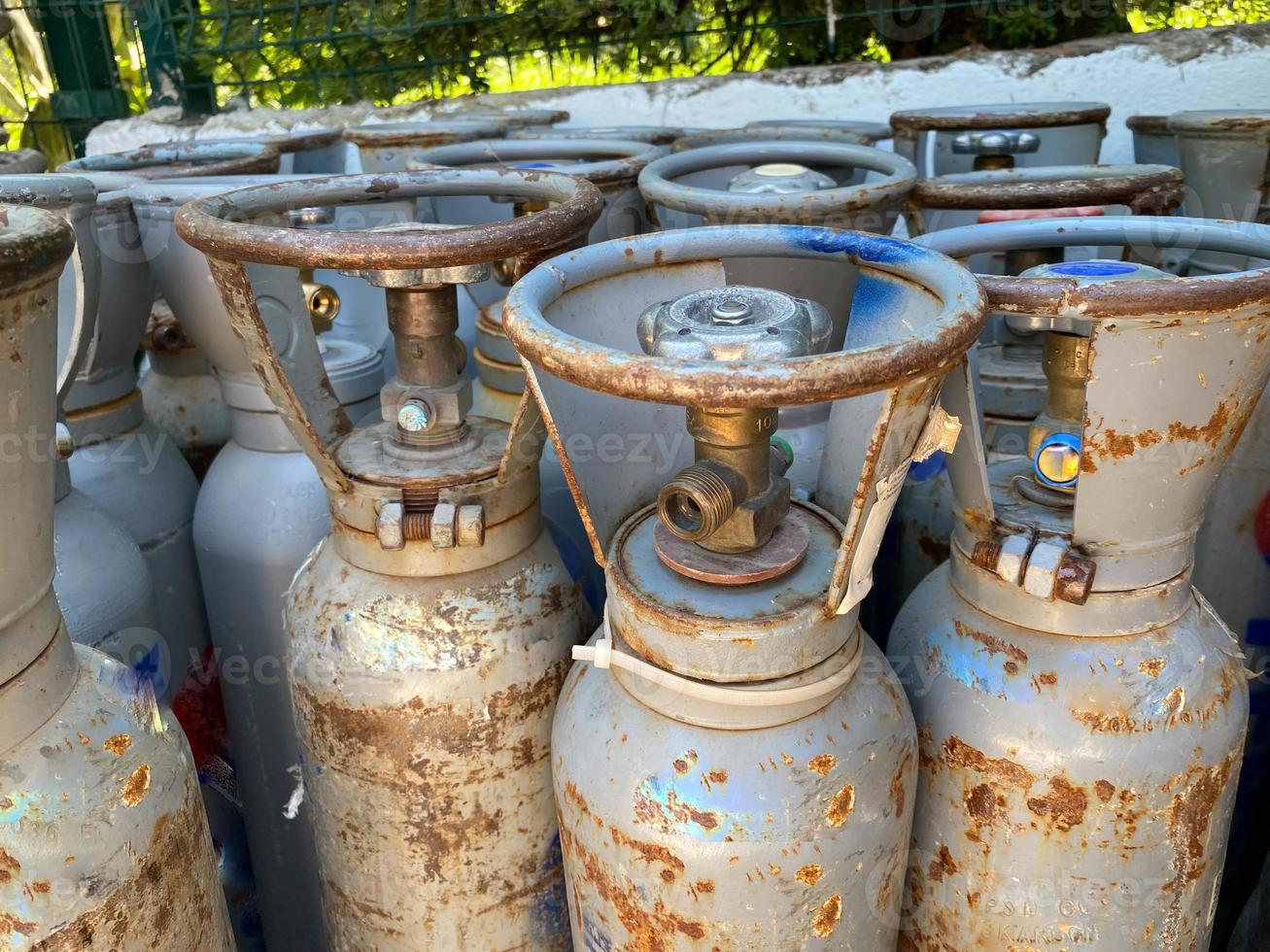 Many various older portable gas cylinders in front of gas store for service photo