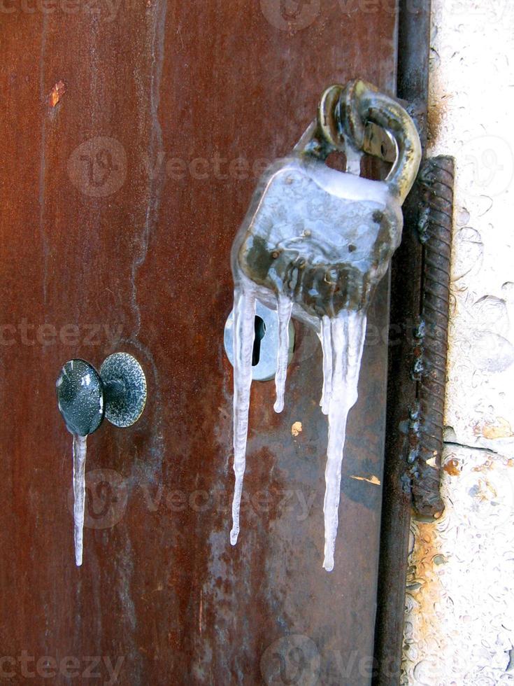 Close up of old rusty lock frozen with icicles photo