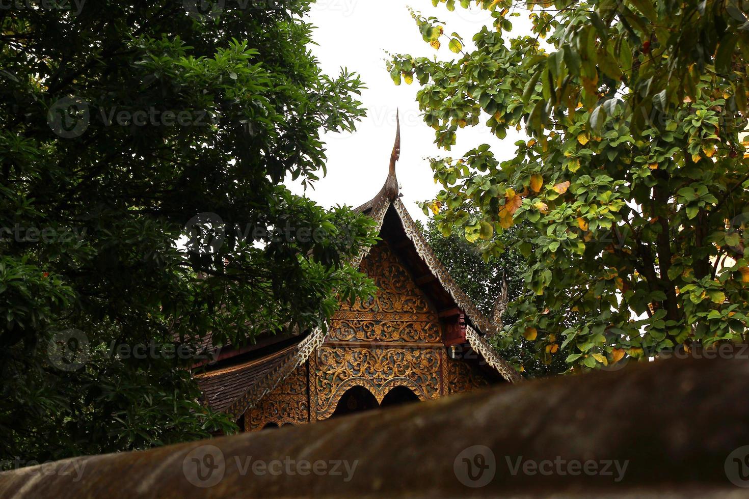 View on a Buddhist temple between trees. Chiang Mai, Thailand. photo