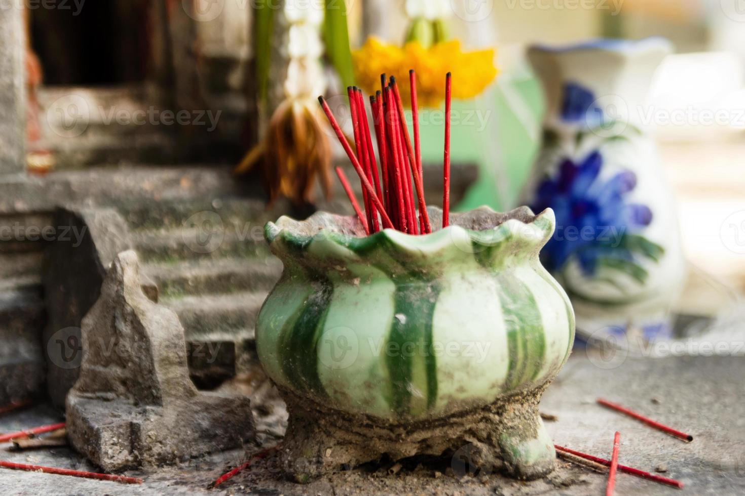 palos rojos de incienso aromático en olla de barro para rezar a buddha o dioses hindúes para mostrar respeto. foto