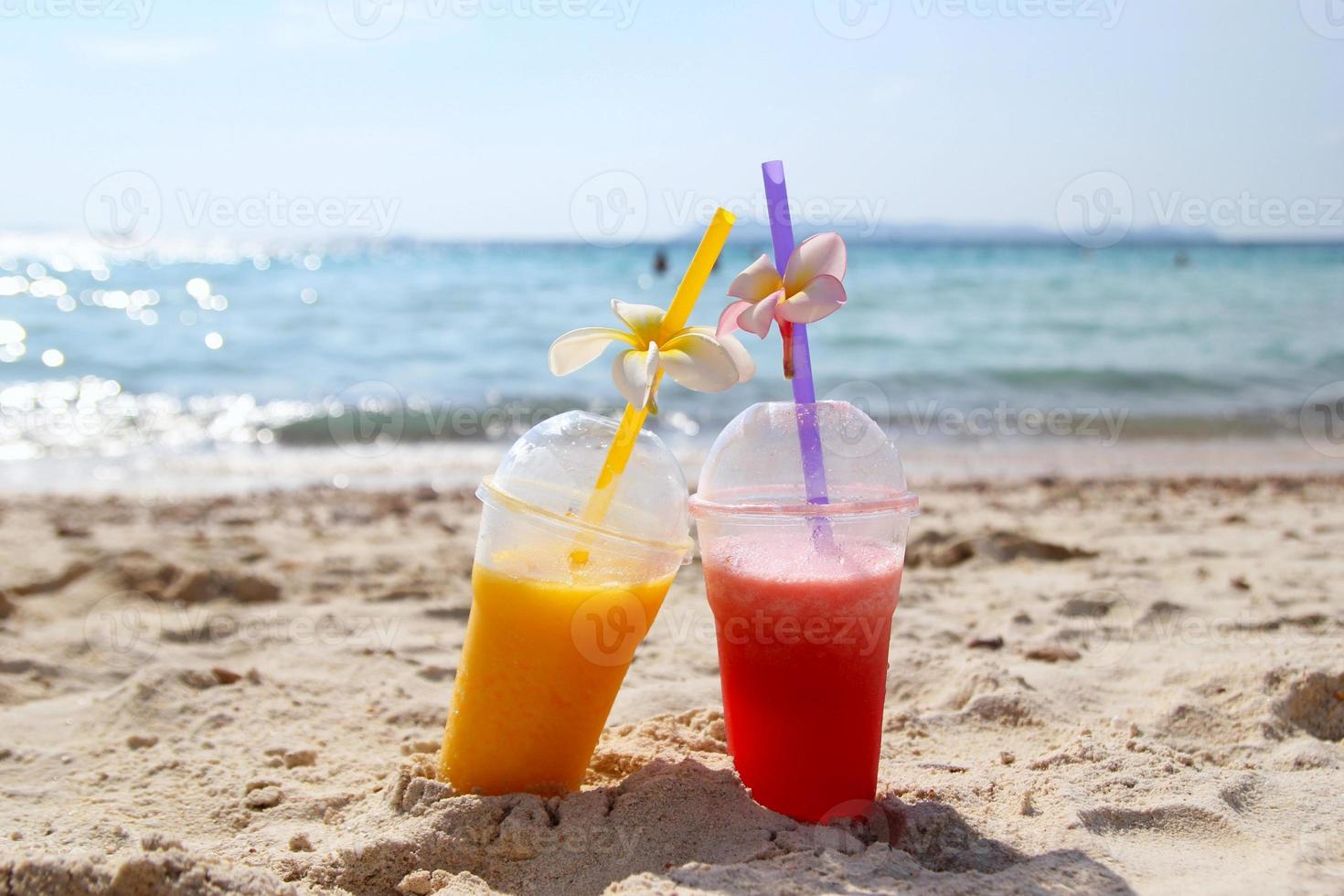 Travel to island Koh Larn, Thailand. Two glasses with mango juice and watermelon juice on the beach in the sunny summer weather. photo