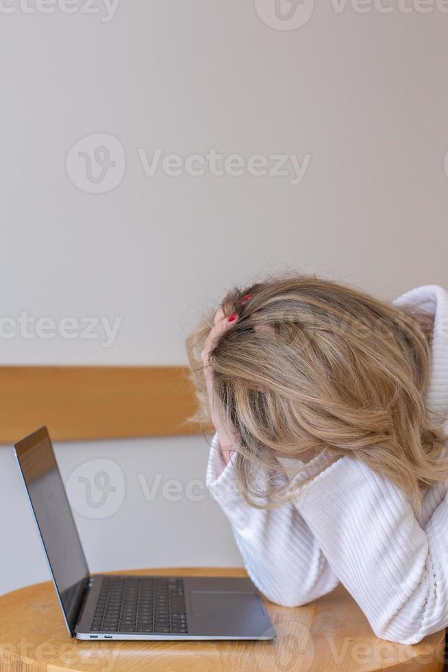 Beautiful girl freelancer feeling tired and stressed while using a laptop and working remotely from home. Business woman at the office is depressed. photo