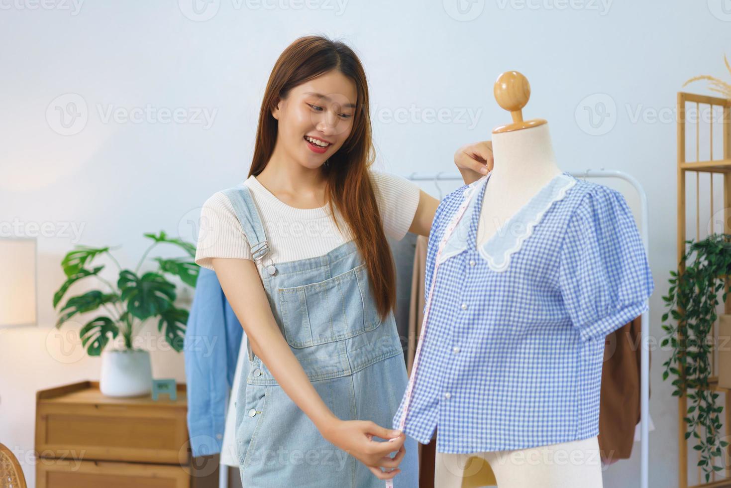 concepto de compras en línea, las mujeres asiáticas miden la longitud de la camisa para presentar y vender en transmisión de video foto