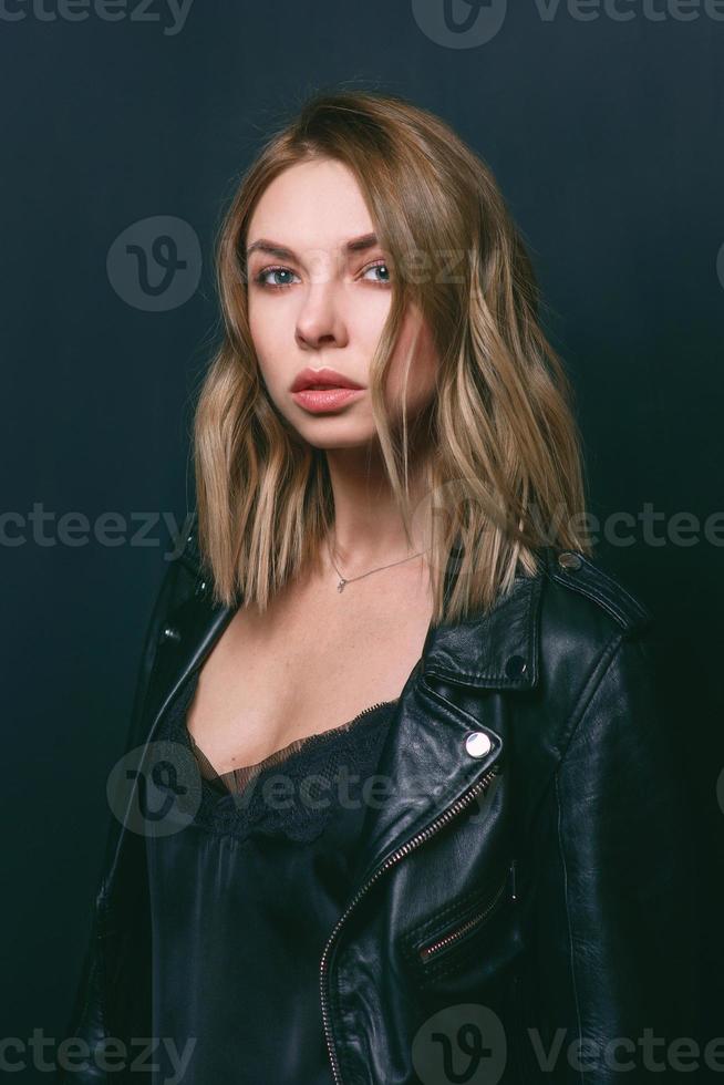 Portrait of the young attractive stylish blonde woman in silk dress and black jacket on the armchair photo