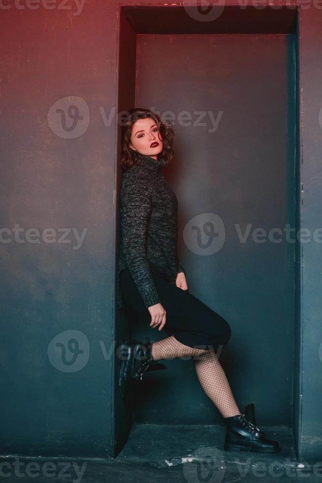 retrato de una hermosa y tierna mujer solitaria deprimida y rizada con un jersey gris en una habitación oscura foto