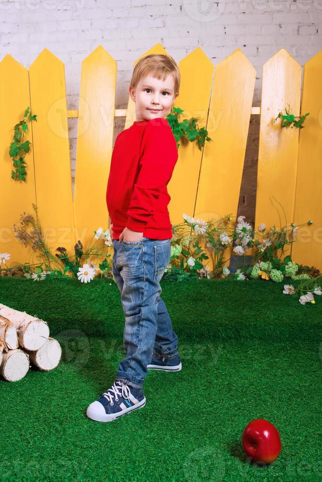 smiling little boy three years old with white puppy of Samoyed on the yellow fence background photo