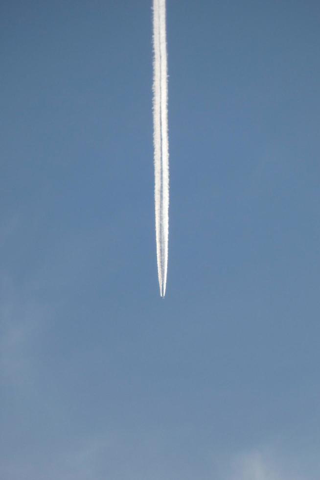 estela blanca de un avión bajo el cielo azul foto