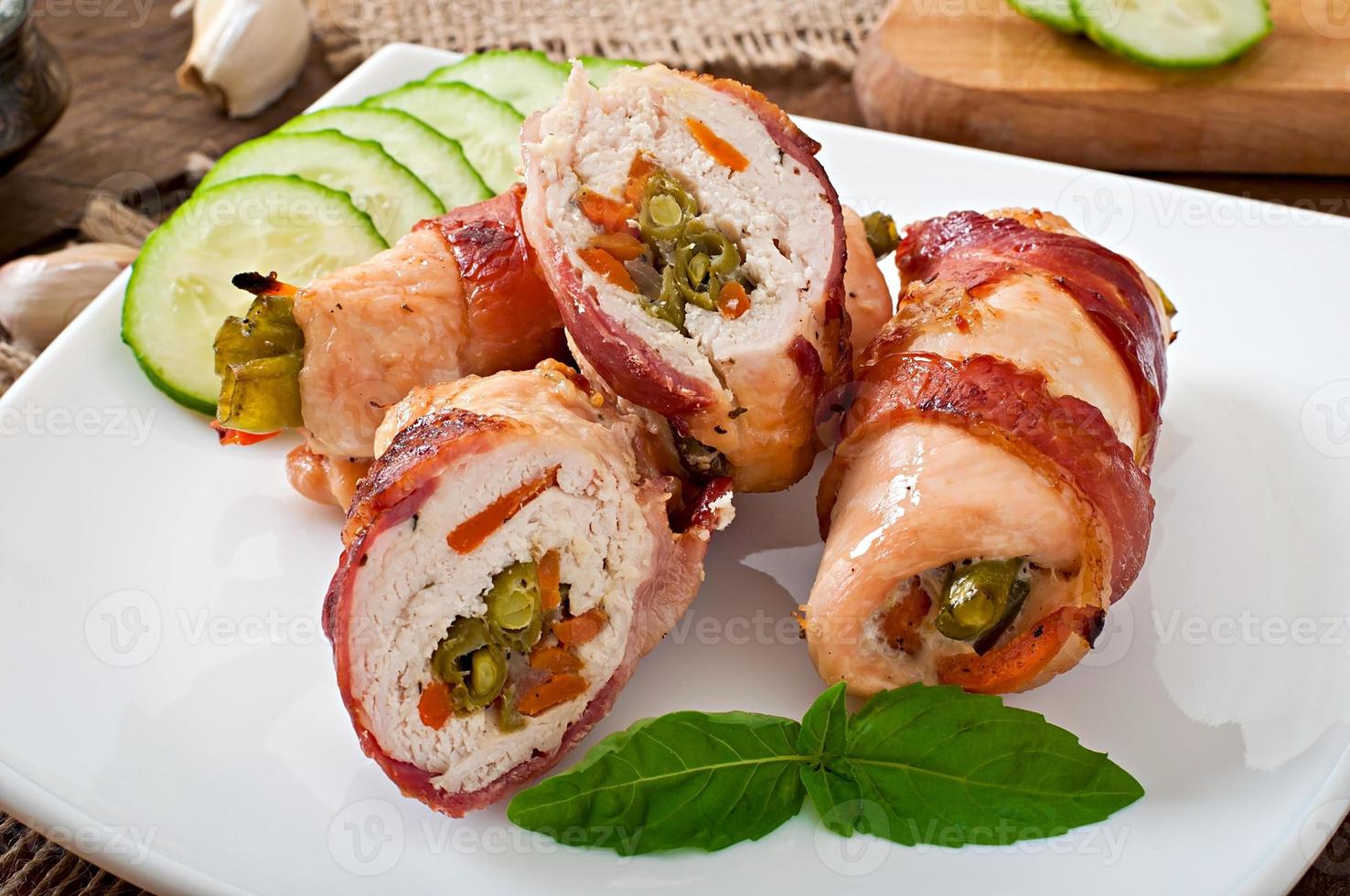 Delicious chicken rolls stuffed with green beans and carrots wrapped in strips of bacon photo