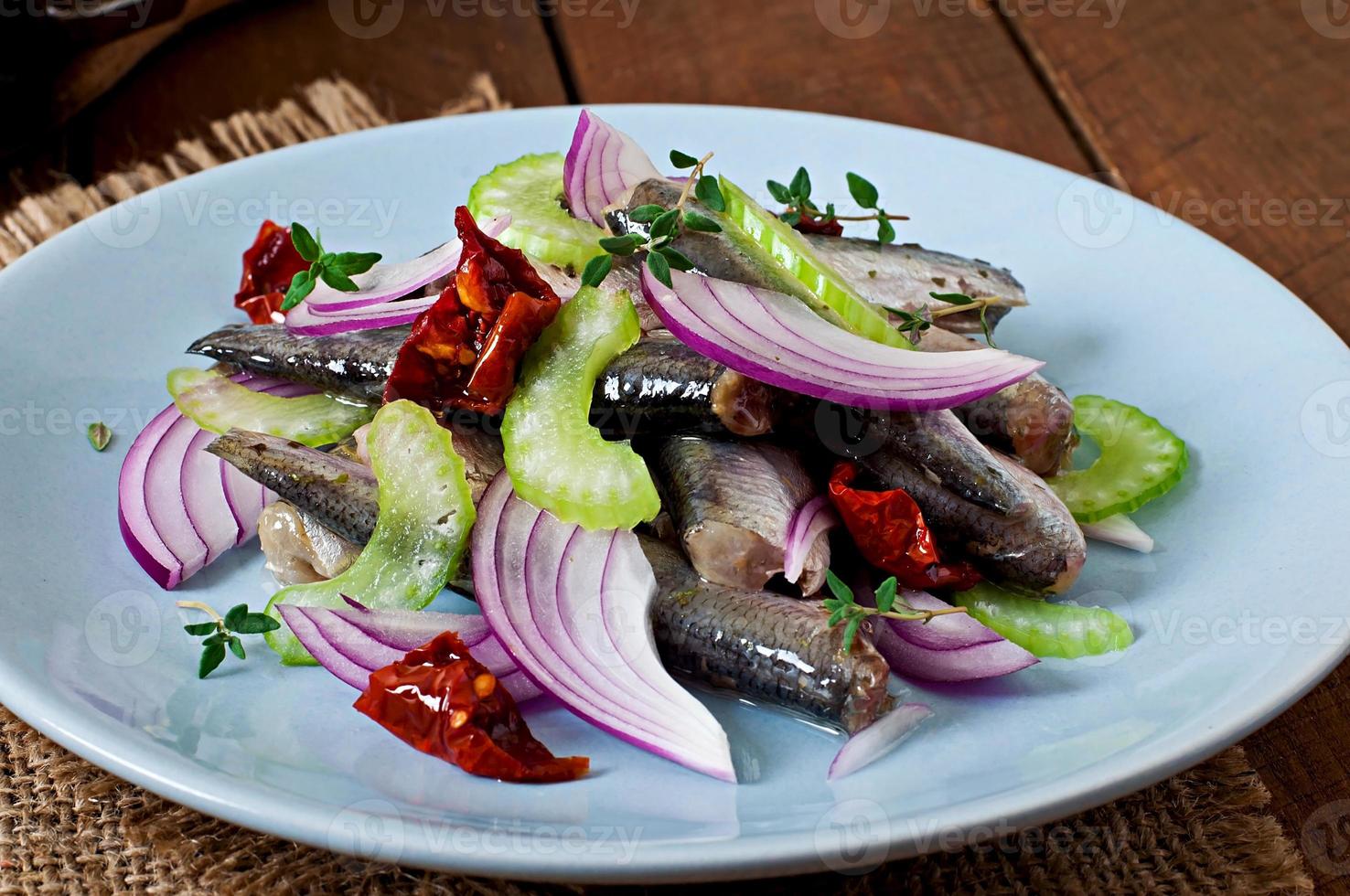 ensalada de arenque con tomates secos, apio y cebolla roja foto