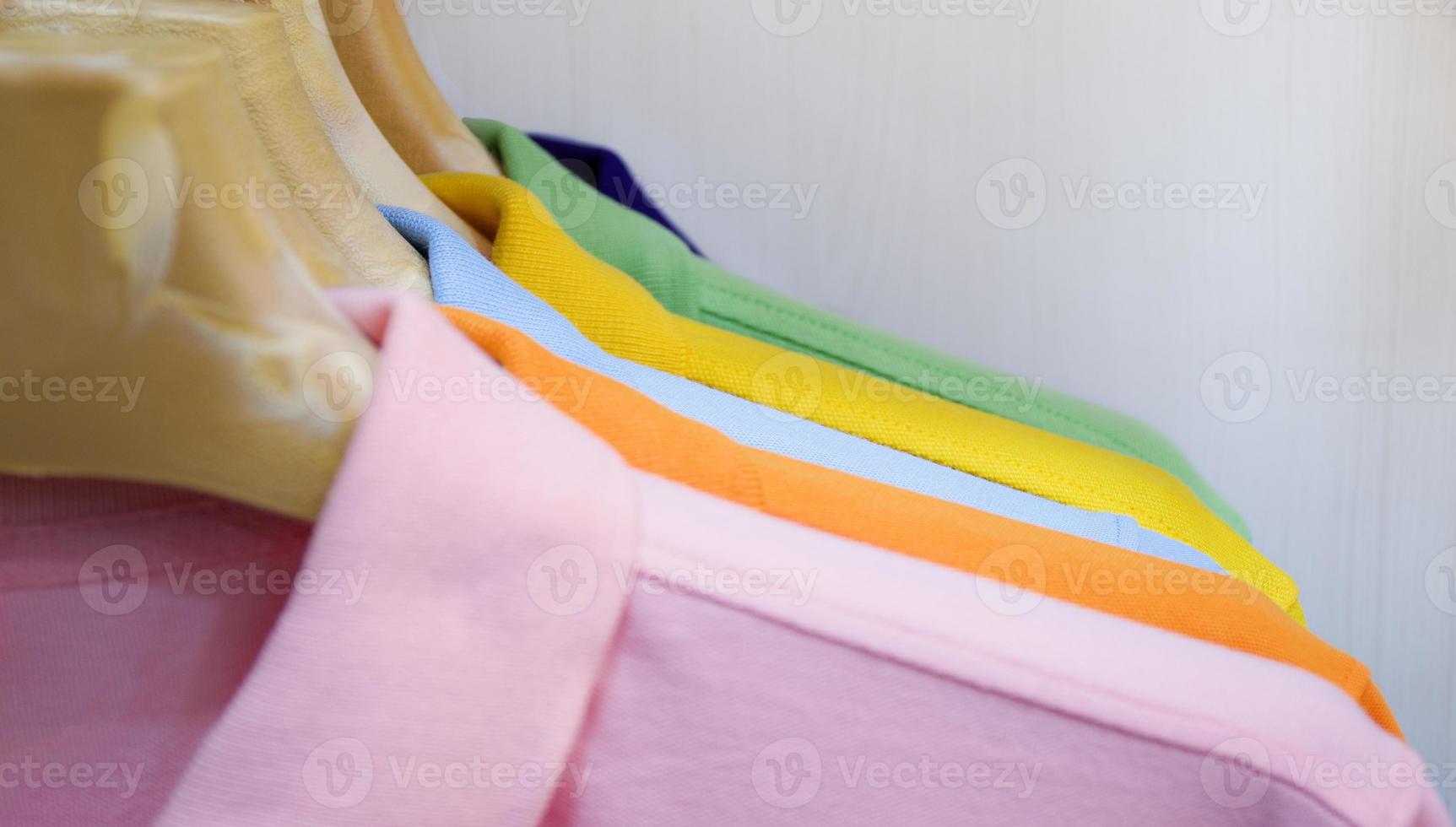 Many colorful shirts hanging on a rack photo