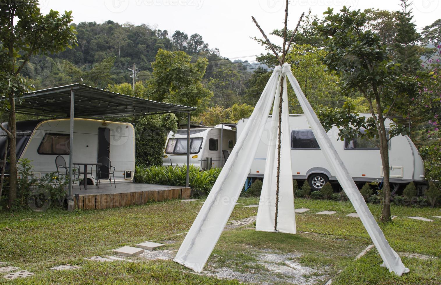 Triangular wooden tents decorated with white cloth with Caravan trailer background photo