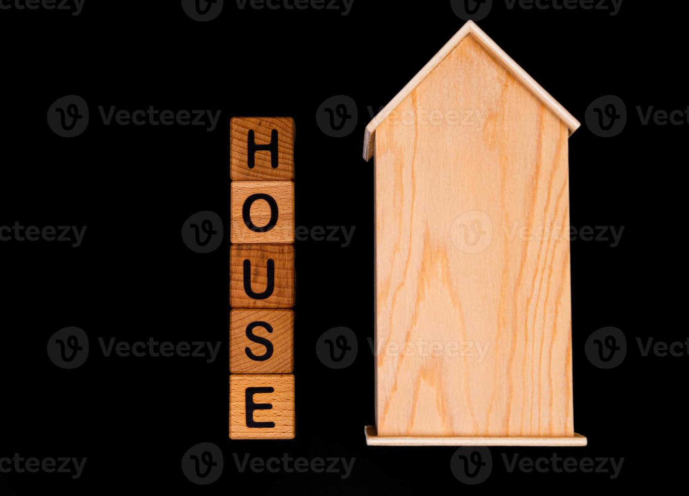 wooden house mockup with house keys, wooden cubes with words rent sale , buy and loan. on black background photo