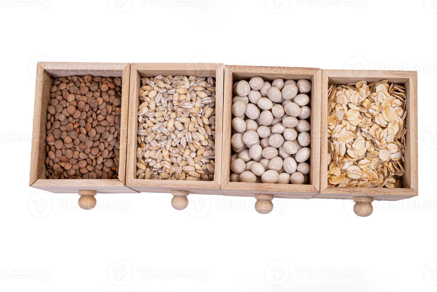 Pattern of raw cereals, beans and seeds, top view texture, mix of groats in square wooden box. Small wooden box with cells with beans lentils oatmeal seeds isolated on white background, photo