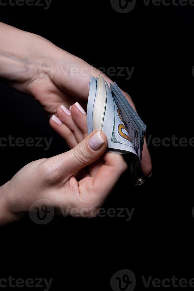 two hands with dollars. Closeup female hand giving money for something with isolated on black background,count, paying, shopping with dollar, corruption, counting dollar banknotes on black photo