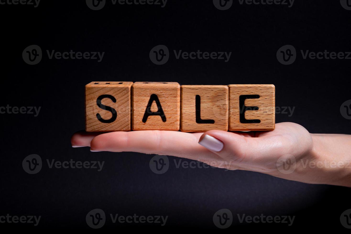 Female hands holds a cube with letters, wooden cubes with words rent sale , buy and loan. Project for designer on black . Words home learn , health photo
