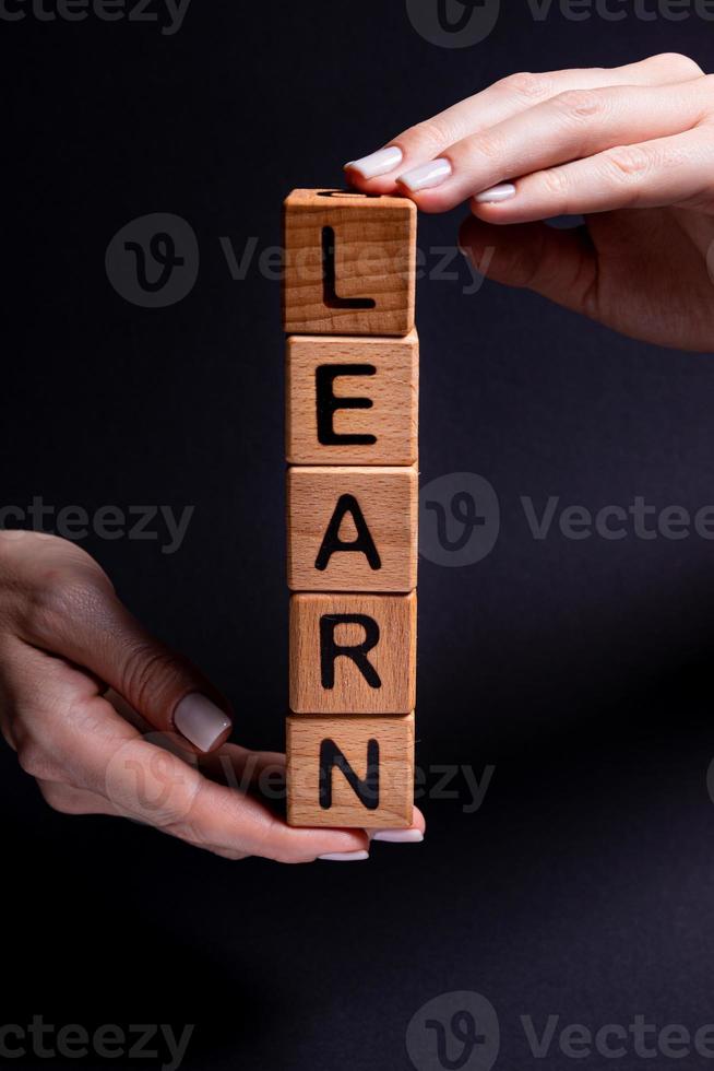 Female hands holds a cube with letters, wooden cubes with words rent sale , buy and loan. Project for designer on black . Words home learn , health photo