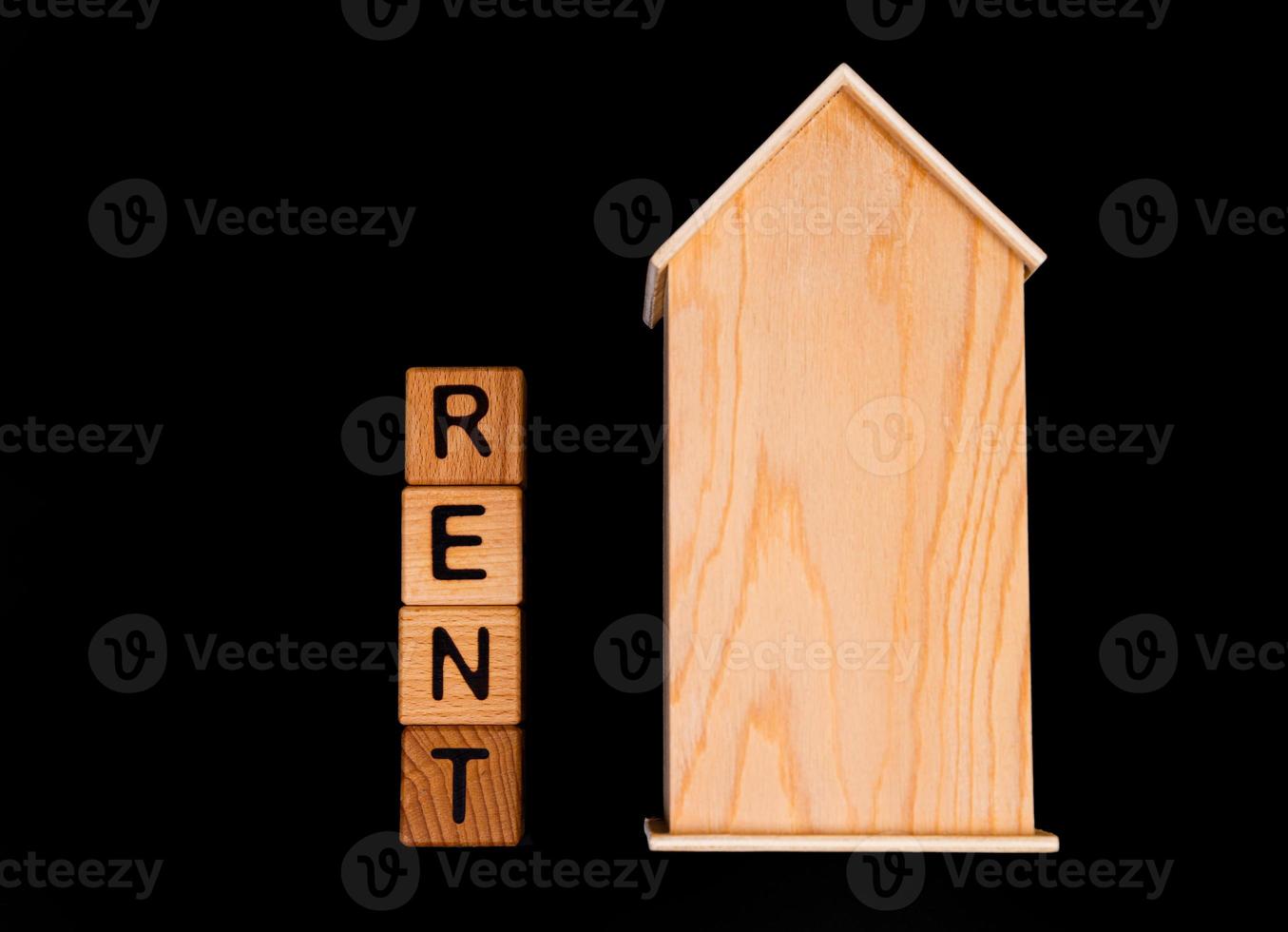 wooden house mockup with house keys, wooden cubes with words rent sale , buy and loan. on black background photo