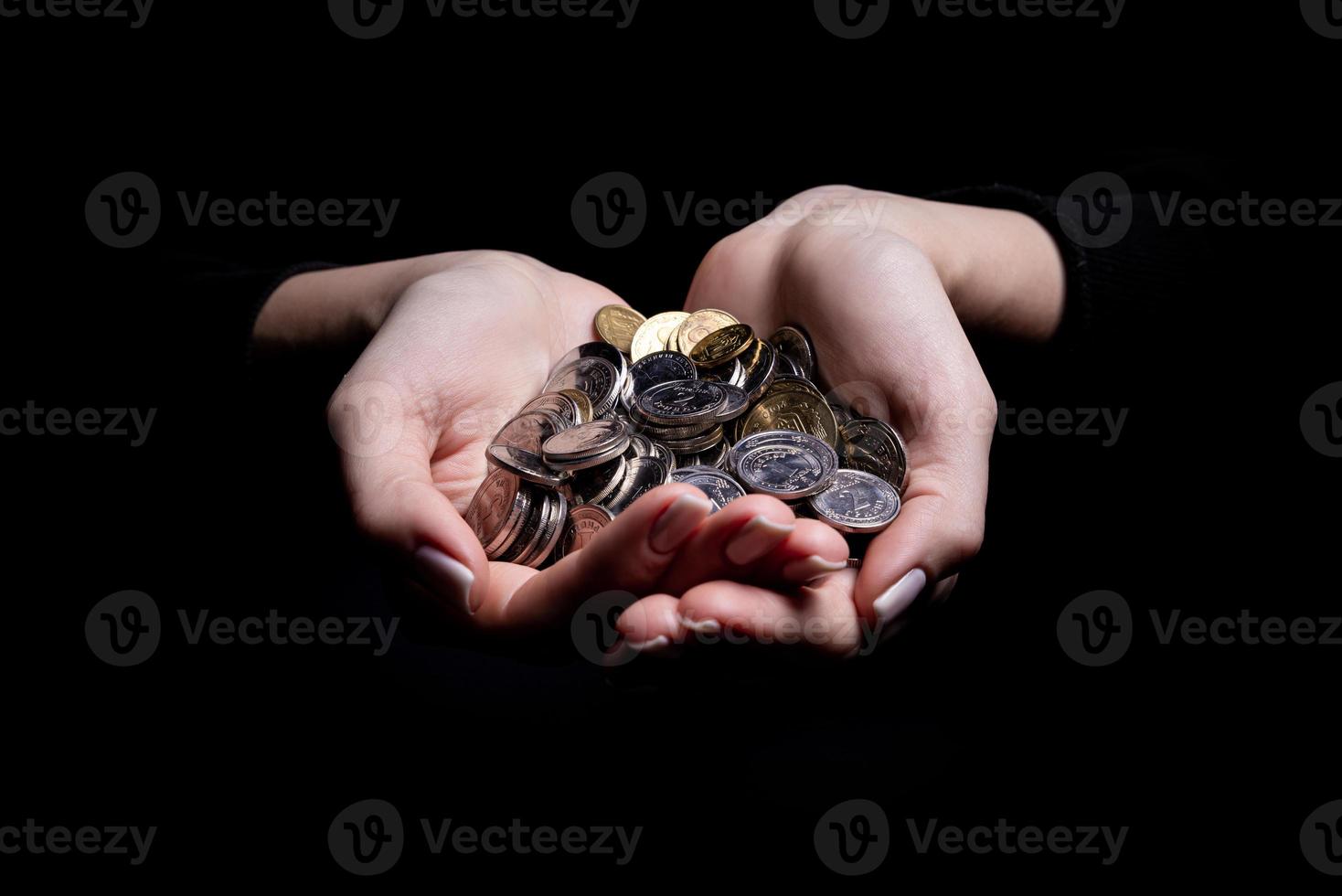 manos sosteniendo monedas enfoque selectivo y suave aislado sobre fondo negro con espacio de copia. foto