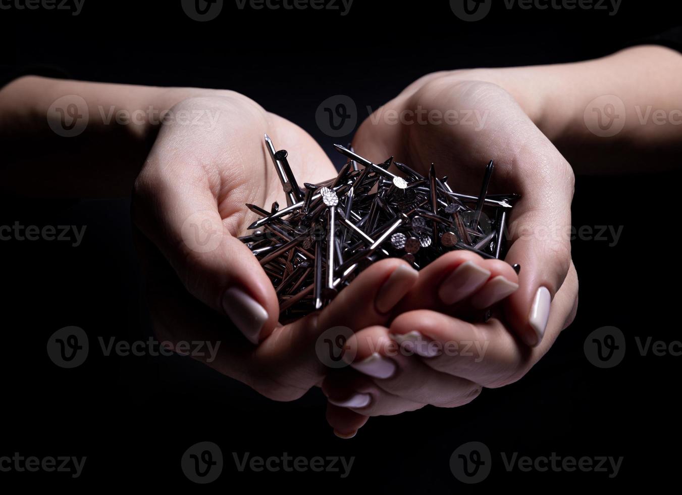 Woman's hands holding screws and dowels in palms. Isolated on black. female hands hold screws nails washers nuts on a black background photo