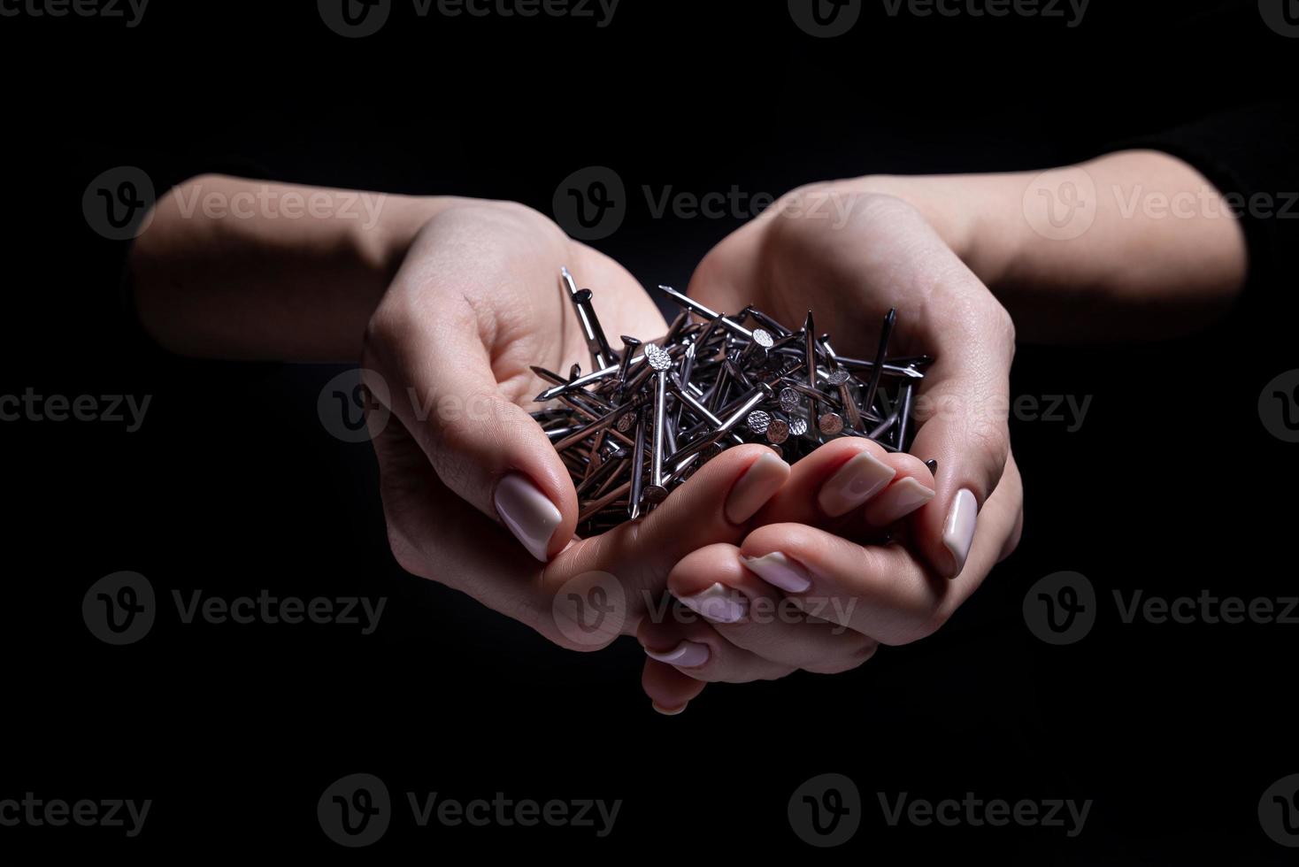 Woman's hands holding screws and dowels in palms. Isolated on black. female hands hold screws nails washers nuts on a black background photo