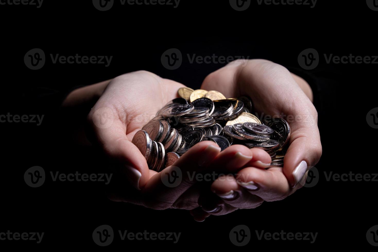 manos sosteniendo monedas enfoque selectivo y suave aislado sobre fondo negro con espacio de copia. foto