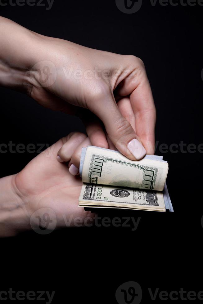 two hands with dollars. Closeup female hand giving money for something with isolated on black background,count, paying, shopping with dollar, corruption, counting dollar banknotes on black photo