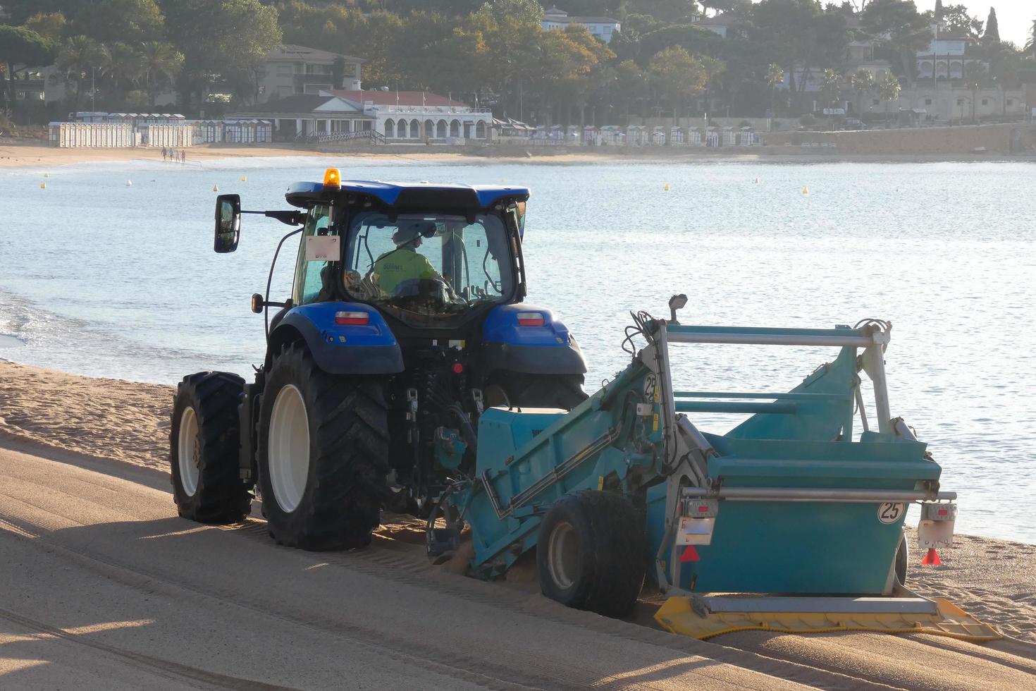 tractor cleaning the white sand on the beach photo