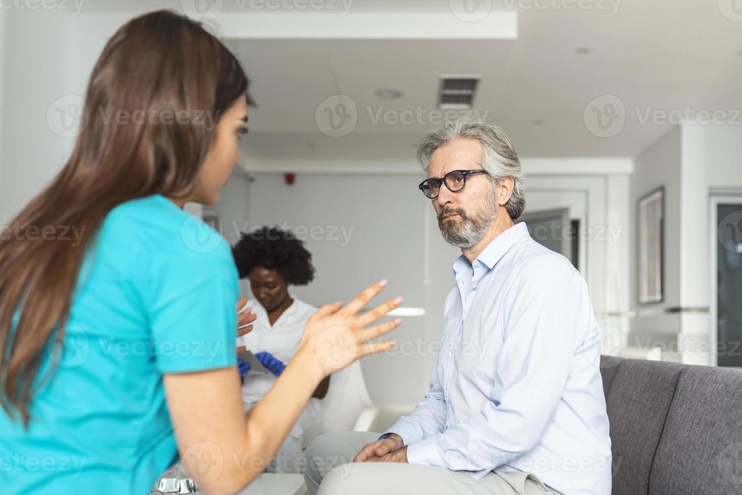 Patient with doctor in hospital waiting room discussing his symptoms. Young female doctor talking with her patient and explaining him his options and therapy photo