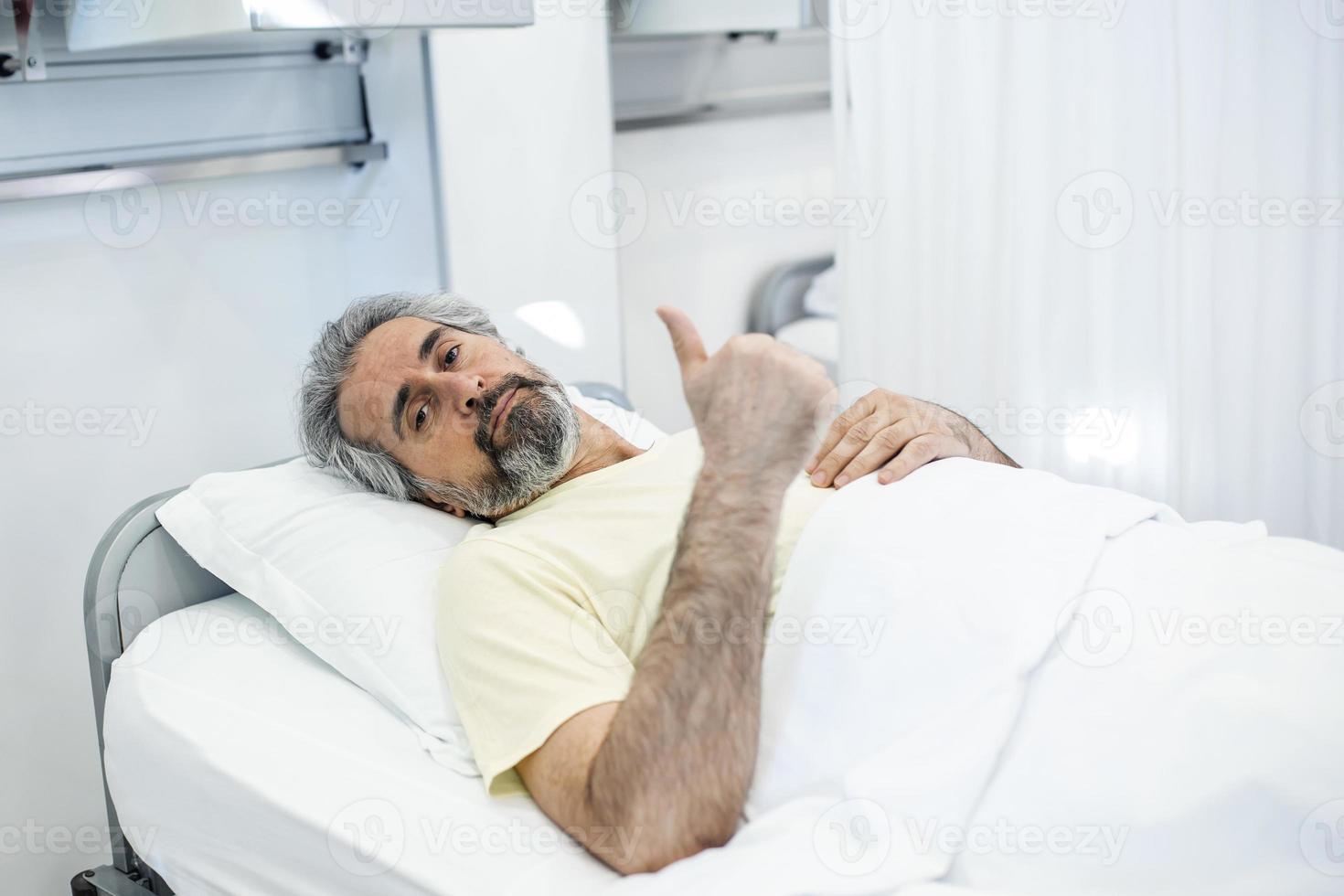 Portrait of retired senior man breathing slowly during coronavirus covid-19 outbreak. Old sick man lying in hospital bed, getting treatment for deadly infection photo