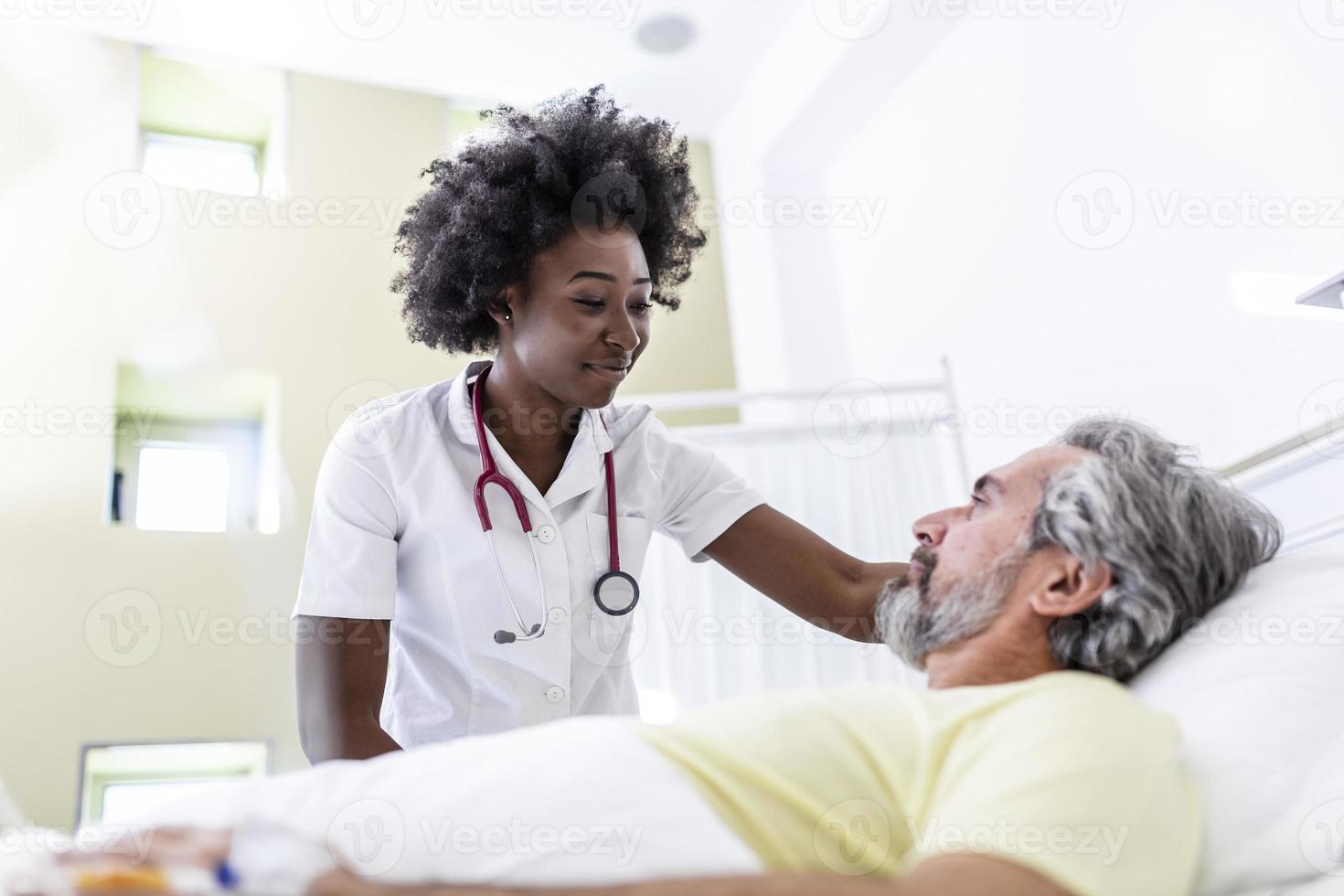 paciente mayor en la cama hablando con una doctora afroamericana en la habitación del hospital, atención médica y concepto de seguro. médico que consuela a un paciente anciano en la cama de un hospital o asesora en el diagnóstico de salud. foto