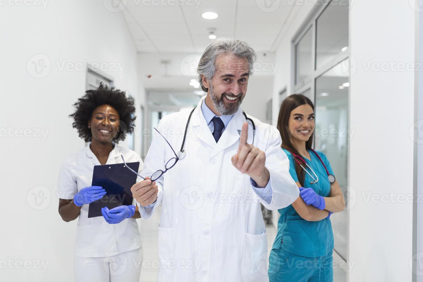 Closeup front view of group of mixed age doctors and nurses standing side by side and looking at the camera. Mature man doctor is in the front photo