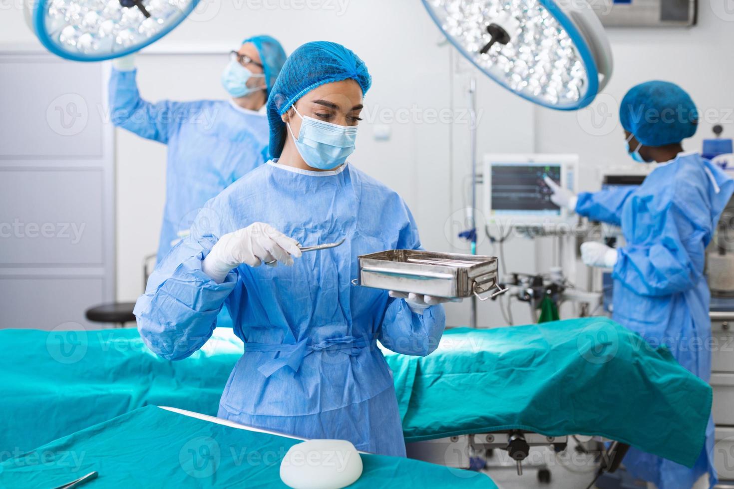 cirujana con uniforme quirúrgico tomando instrumentos quirúrgicos en el quirófano. joven doctora en el quirófano del hospital foto