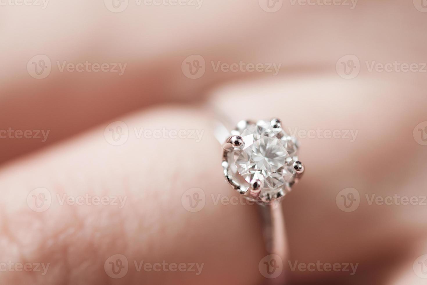 Close up of an elegant engagement diamond ring on woman finger photo