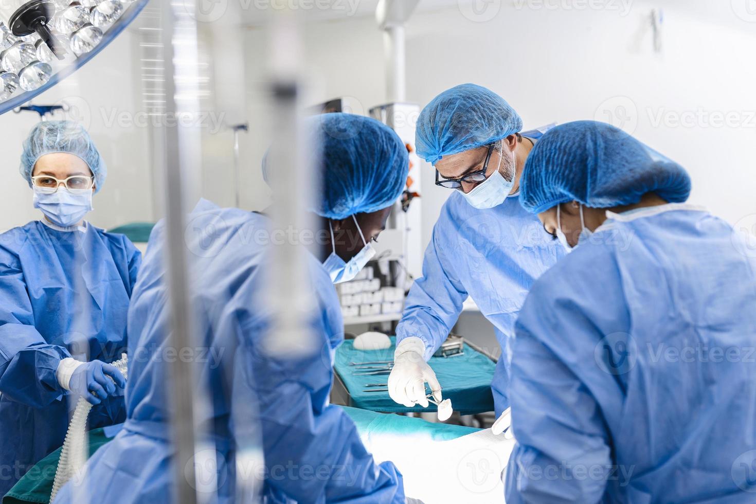 Diverse Team of Professional surgeon, Assistants and Nurses Performing Invasive Surgery on a Patient in the Hospital Operating Room. Surgeons Talk and Use Instruments. Real Modern Hospital. photo