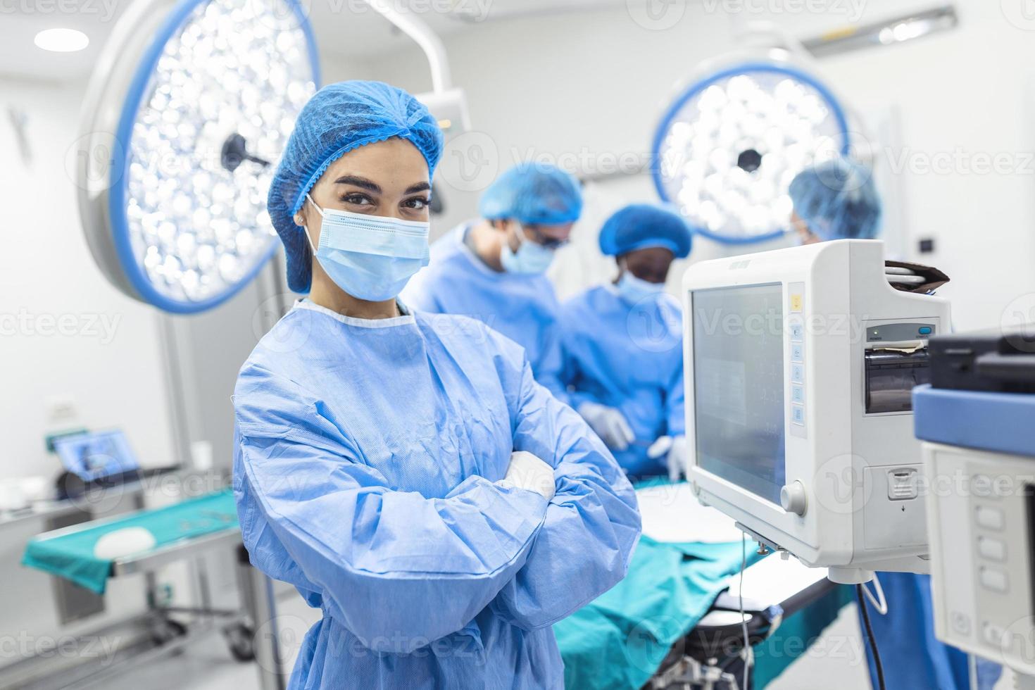 Anesthesiologist keeping track of vital functions of the body during cardiac surgery. Surgeon looking at camera. Doctor checking monitor for patient health status. photo