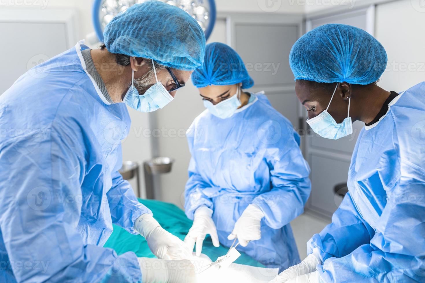 grupo de cirujanos que realizan cirugía en el quirófano del hospital. equipo médico que realiza una operación crítica. grupo de cirujanos en quirófano con equipo quirúrgico. antecedentes médicos modernos foto