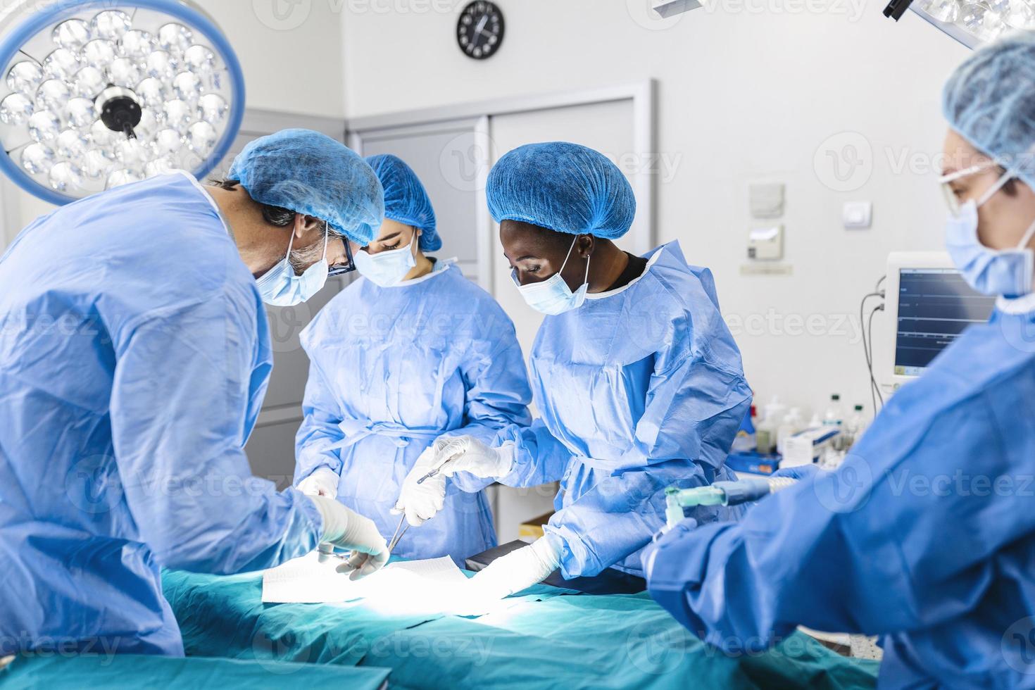 equipo quirúrgico que realiza cirugía en el quirófano moderno, equipo de médicos que se concentran en un paciente durante una cirugía, equipo de médicos que trabajan juntos durante una cirugía en el quirófano, foto
