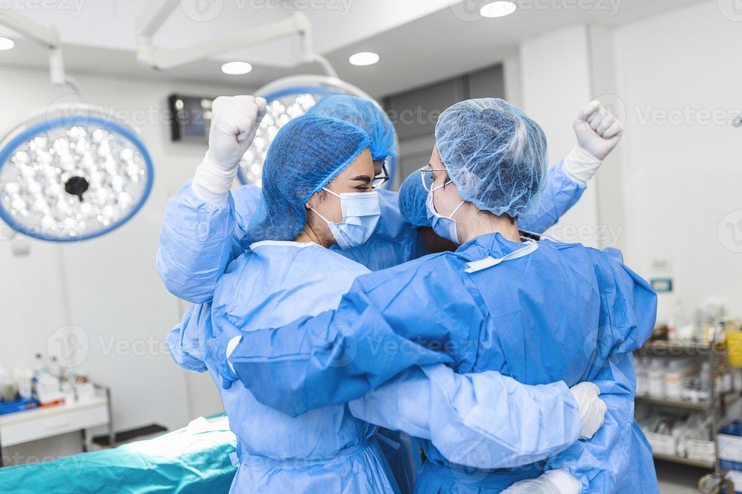 Partial view of hard-working male and female hospital team in full protective wear standing together in group embrace. photo